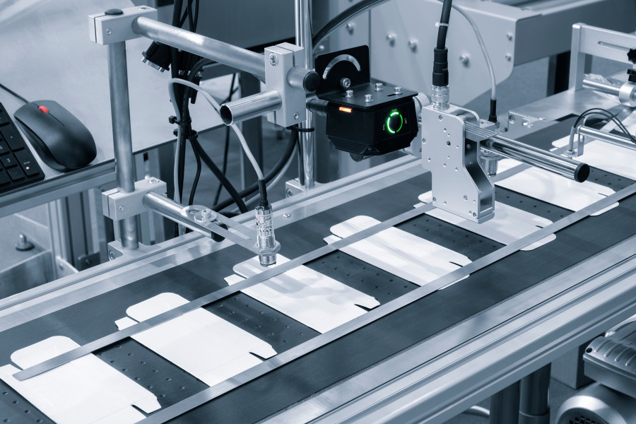 materiały partnera Maszyna do pakowania produktów w kartoniki – zbliżenie na mechanizm bocznego wsuwania towaru w kartoniarce poziomej.